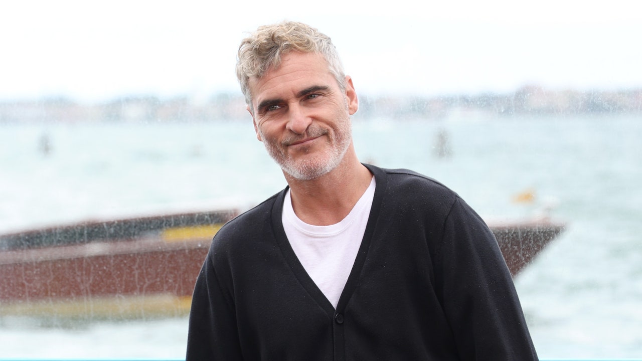 Actor Joaquin Phoenix standing in front of luxury real estate properties.