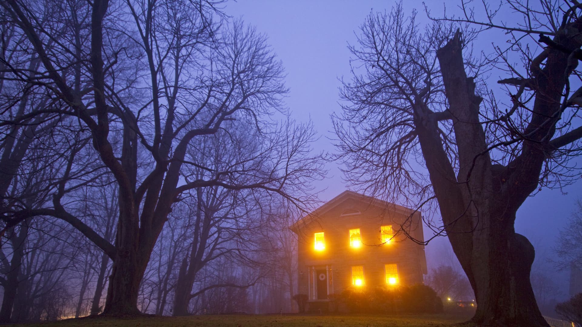 Real estate agent standing in front of a house with a somber expression.