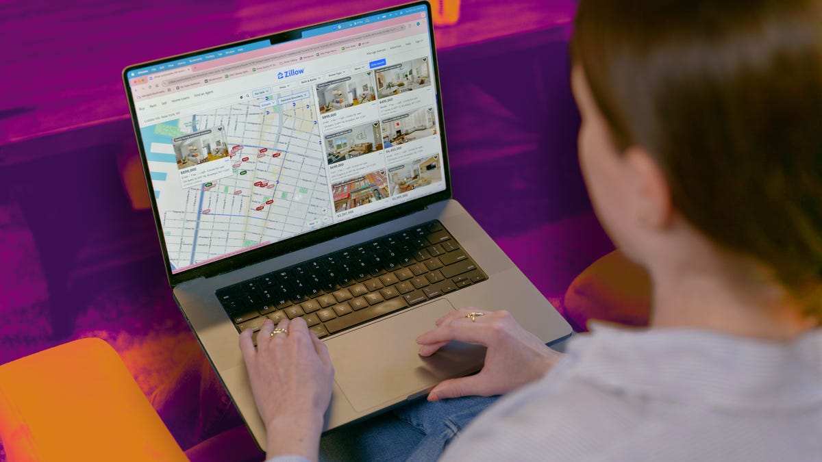 Person browsing online real estate on laptop, surrounded by unaffordable home listings.