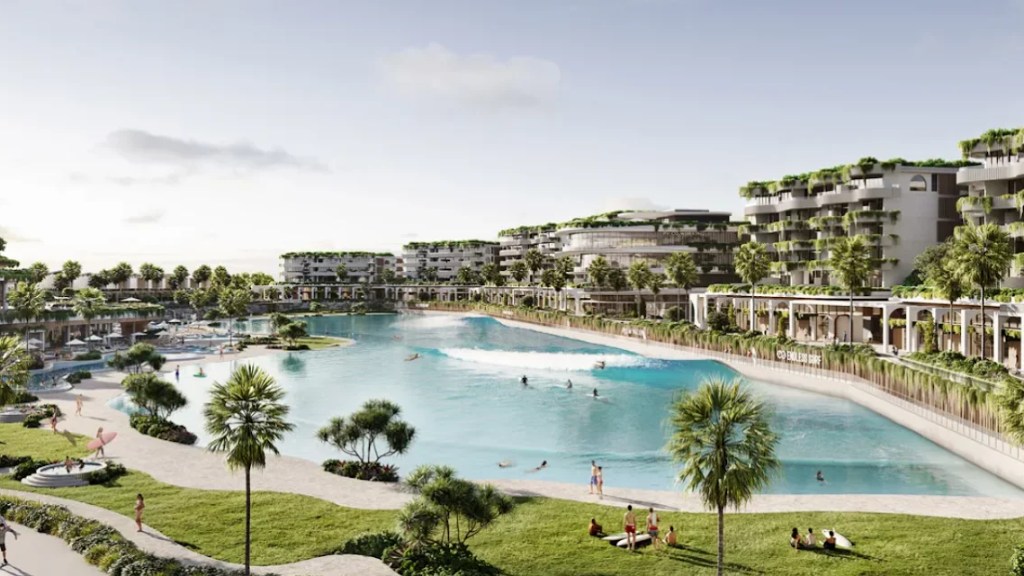 Surfers ride waves at inland surf park development in California desert landscape.