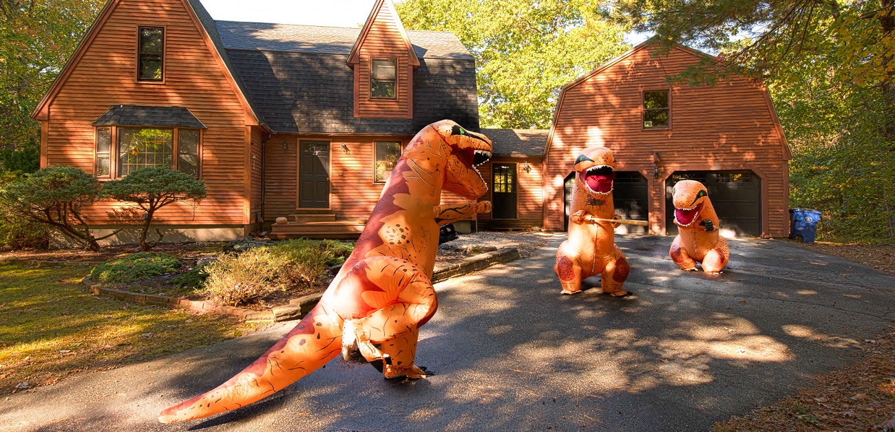 New Hampshire realtor stands in front of prehistoric-themed property for sale.