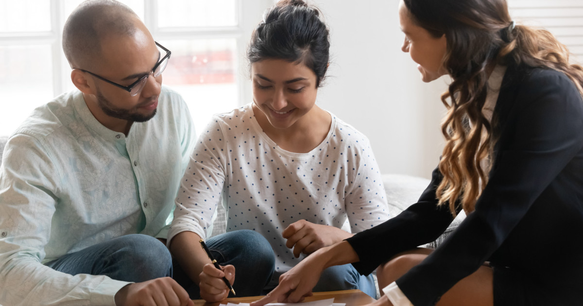 Homebuyers reviewing documents with realtor at closing table in a modern office.