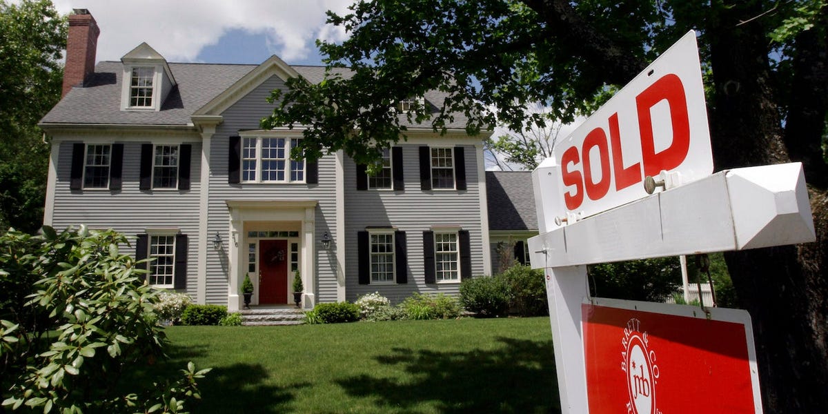 Real estate experts gather near a house, predicting home sales rebound.