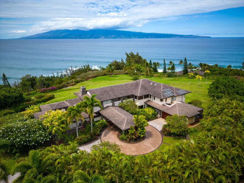 Solar-powered luxury mansion in Hawaii with lush tropical surroundings and ocean views.