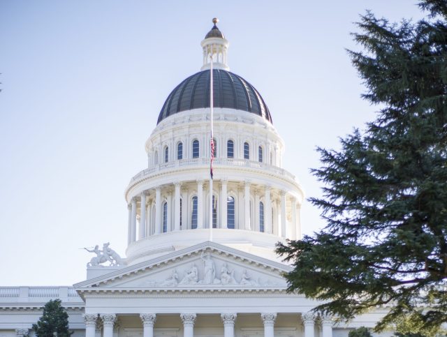 California lawmakers surrounded by lobbyists amidst affordable housing transparency controversy debate.