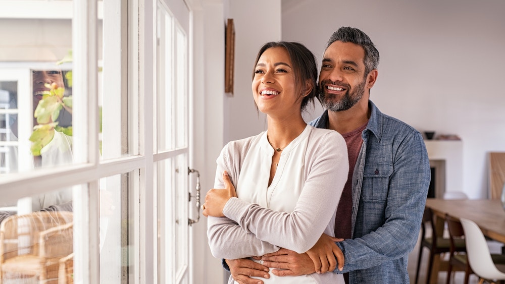 Unmarried couple discusses finances while looking at house plans together.