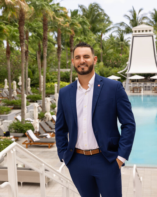 Dexter Avney standing on a tropical beach, showcasing luxury island real estate properties.