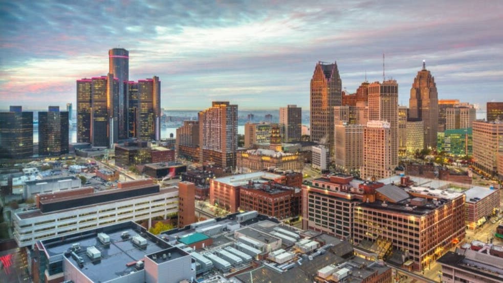 Detroit skyline with construction cranes, highlighting real estate market growth and investment opportunities.