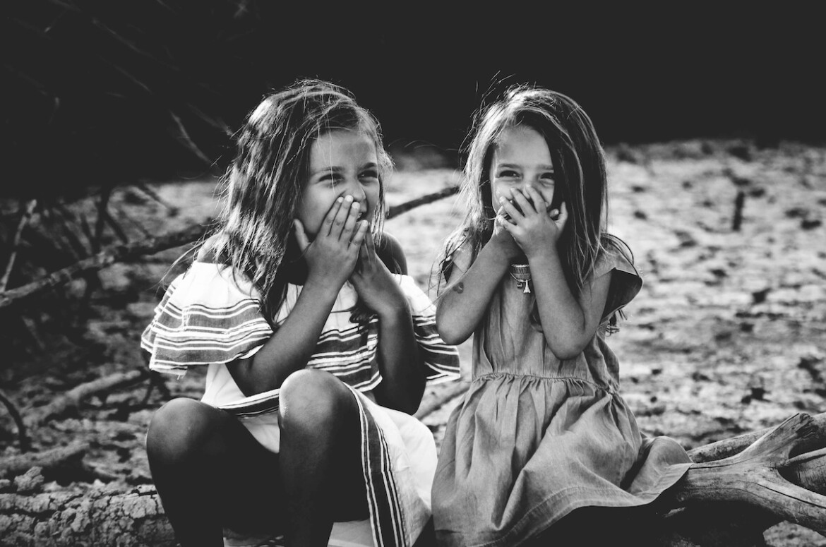 Vintage photograph of children playing together in a sunny backyard setting.