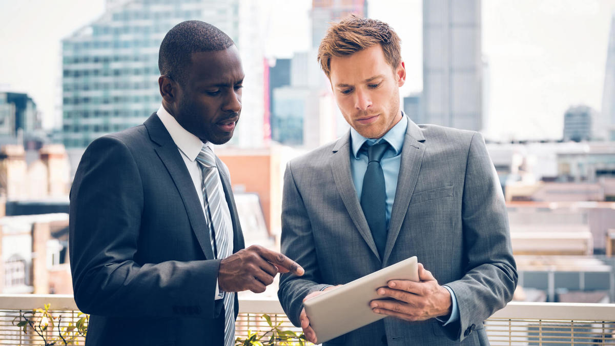 Real estate investors gather around a globe with financial charts and maps.