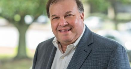 Businessman in office, with cityscape background, expanding into residential market.