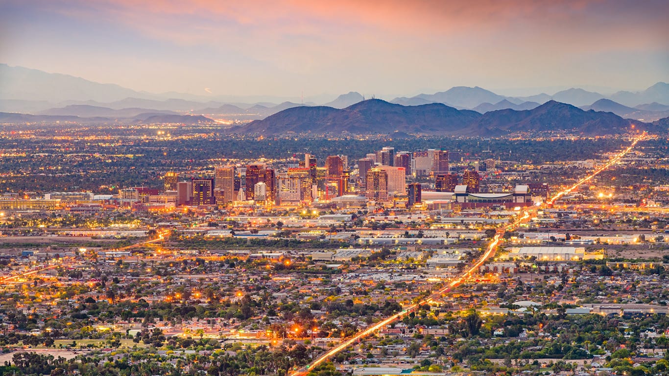 Phoenix skyline with cranes, buildings, and desert landscape, highlighting commercial growth.