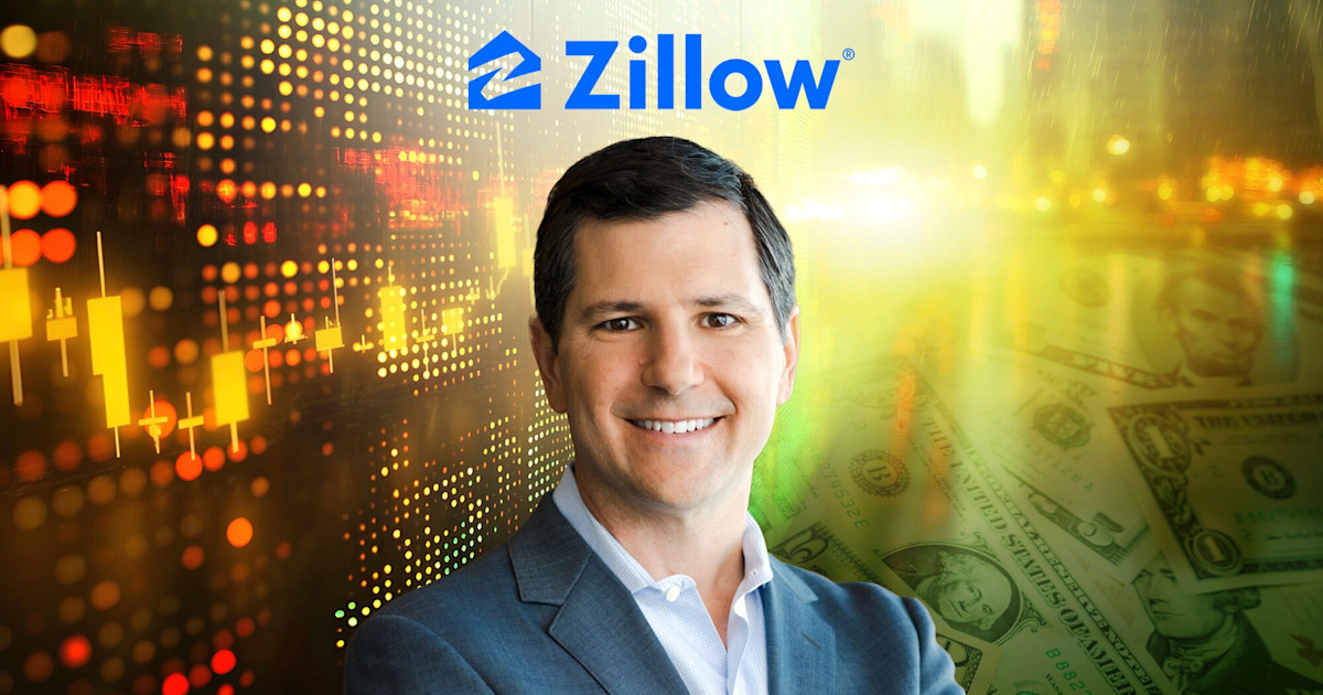 Zillow executive stands in front of a city skyline, holding a smartphone.