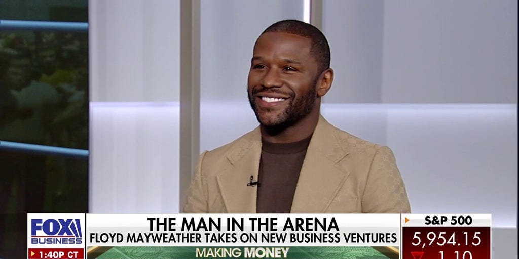 Floyd Mayweather stands in front of luxury real estate development, Las Vegas skyline.