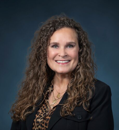 Premier Real Estate executive Kristin Cannoot poses in office setting, smiling.