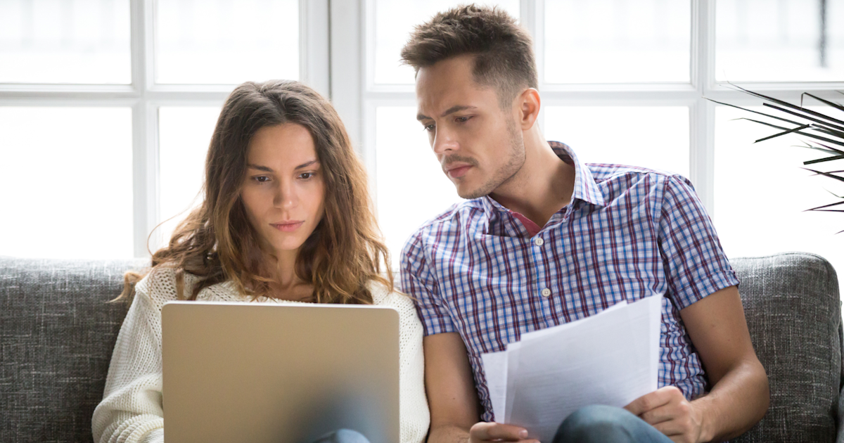 Homebuyers standing in front of a house, uncertain about spring market prospects nationwide.